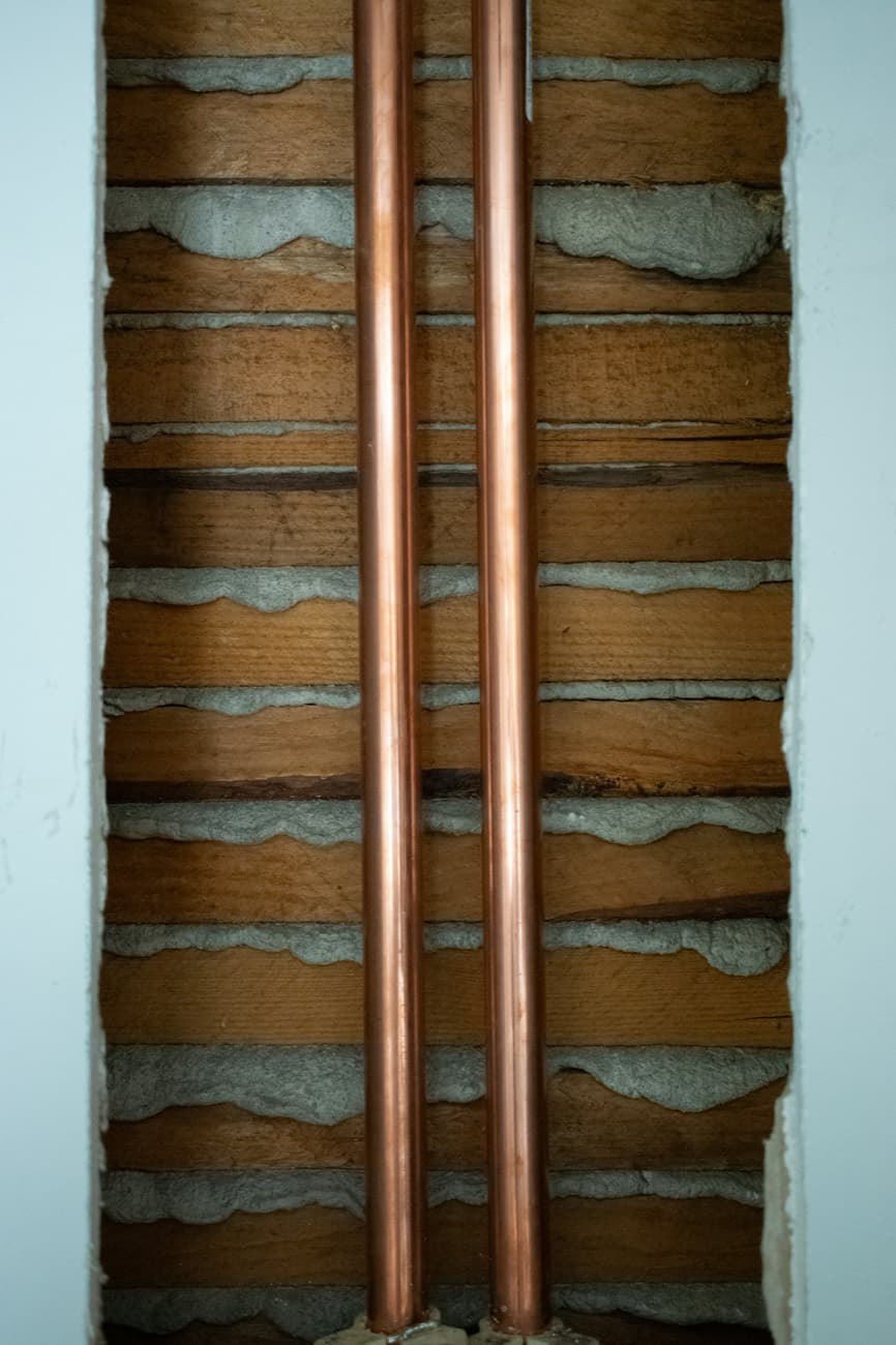 New copper pipework running neatly through a stud wall, installed by Fettle